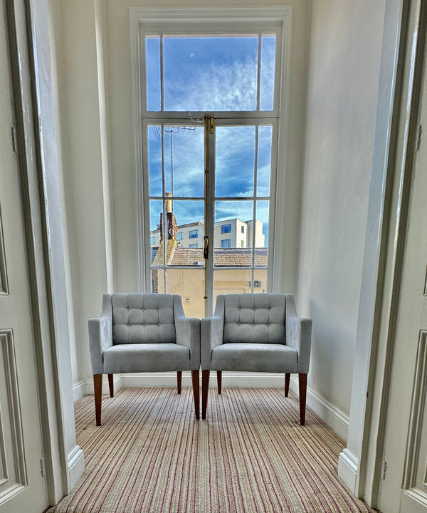 Quiet consultation seating alcove with armchairs by sash window